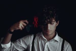 man in white dress shirt holds red flower
